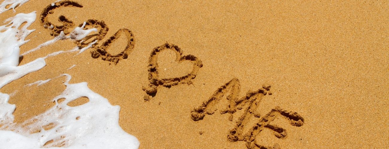 God Love Me written in sand on beach