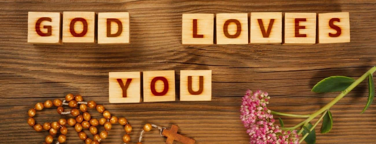 God Loves You spelled out in blocks with rosary and flowers