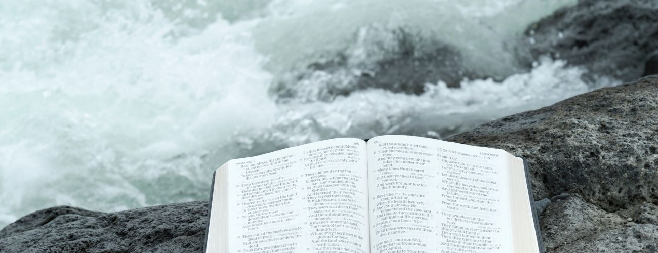 Bible sitting on rocks looking down at ocean waves