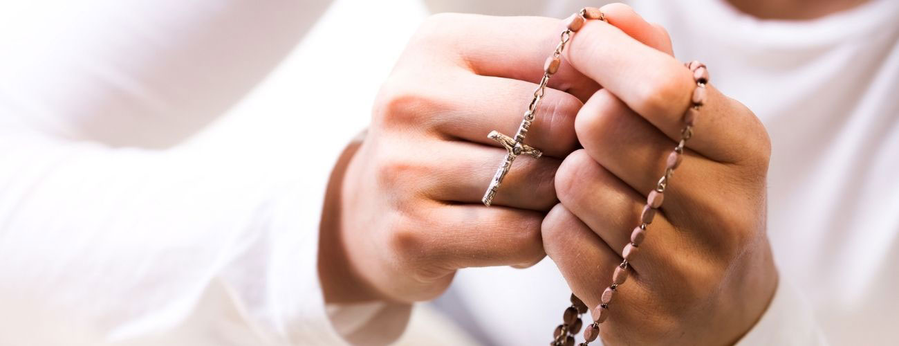 female hands praying and holding rosary